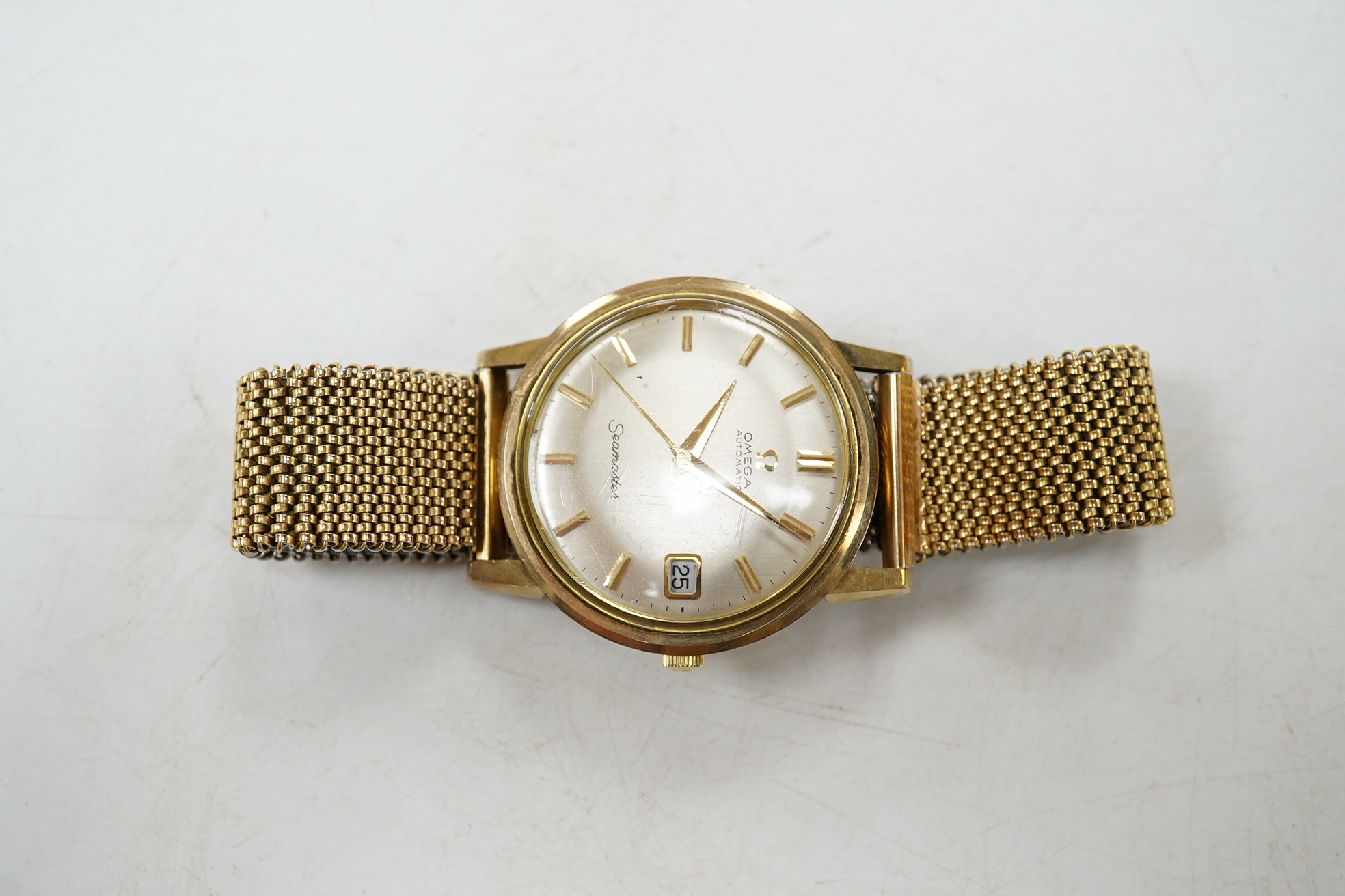 A gentleman's 9ct gold Omega Seamaster Automatic wrist watch, with baton numerals and date aperture, on an associated flexible bracelet, case diameter 35mm. Condition - fair